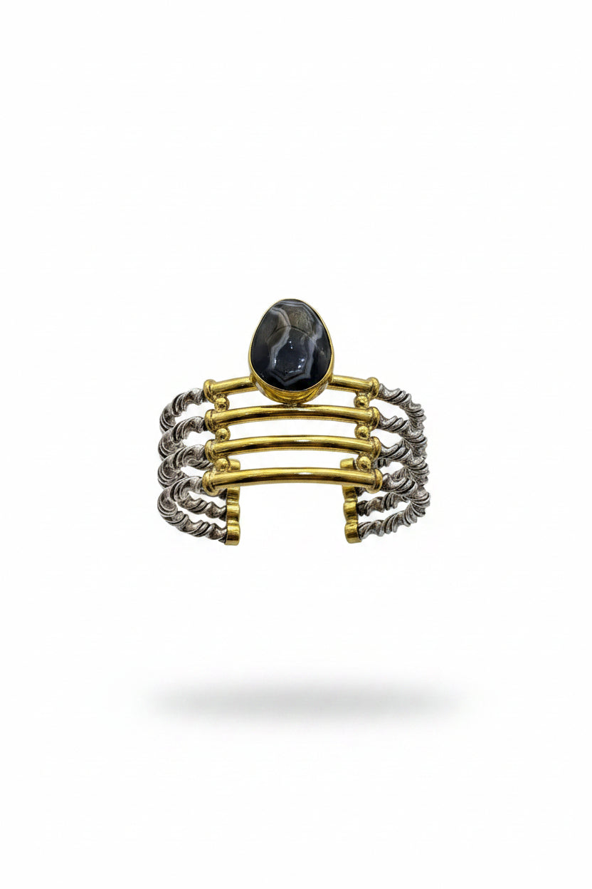 Hand holding a stack of three bracelets against a plain background