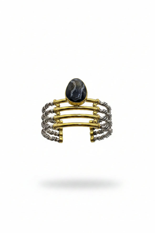 Hand holding a stack of three bracelets against a plain background