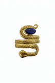 Gold snake-shaped bracelet with a blue stone held in front of a laptop on a desk.