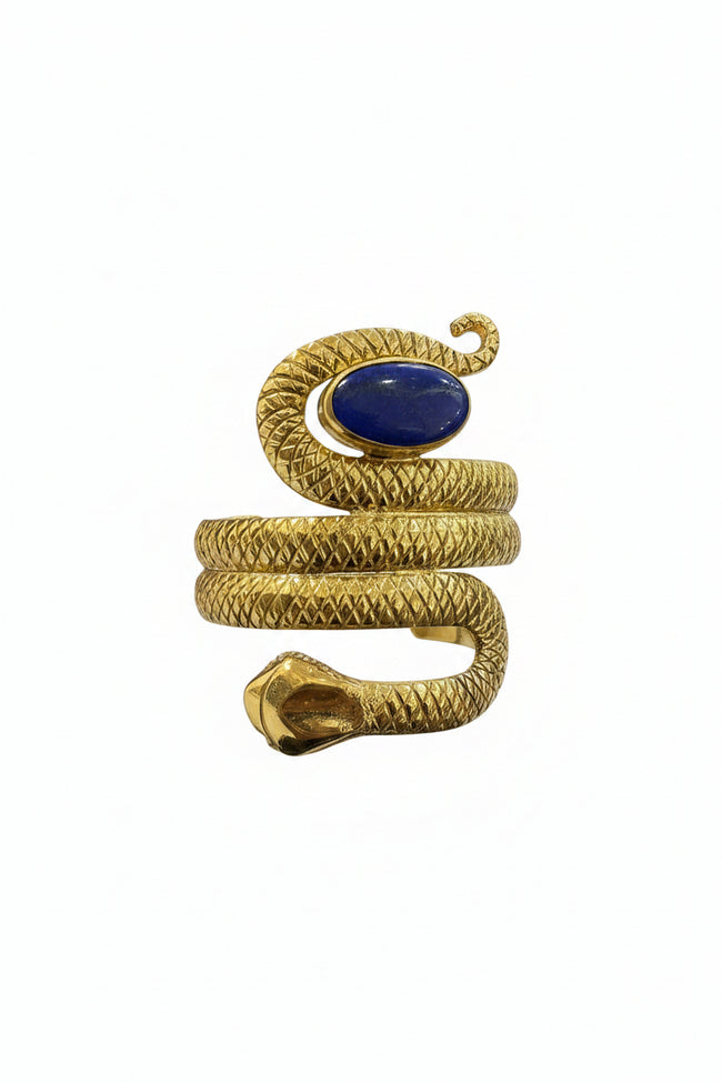 Gold snake-shaped bracelet with a blue stone held in front of a laptop on a desk.